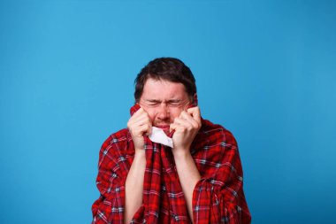 Hasta bir adam, battaniyeye sarılmış, elinde beyaz bir mendil tutuyor..