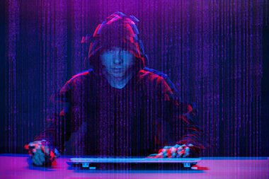 Hacker etrafında dijital arayüz ile karanlık odada bilgisayar ile çalışıyor. Aksaklık efektli görüntü.