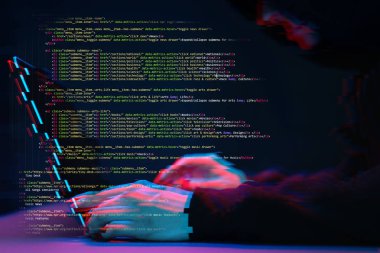 Hacker etrafında dijital arayüzü ile karanlık odada dizüstü bilgisayar ile çalışıyor. Glitch efektli görüntü.