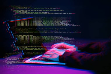 Hacker etrafında dijital arayüzü ile karanlık odada dizüstü bilgisayar ile çalışıyor. Glitch efektli görüntü.