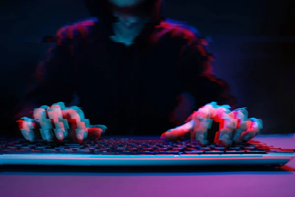 Hacker w kaptur pracy z komputerem wpisując tekst w ciemnym pomieszczeniu. Obraz z efektem glitch — Zdjęcie stockowe