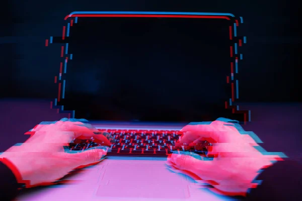 Hacker in the hood working with laptop typing text in dark room. Image with glitch effect — Stock Photo, Image