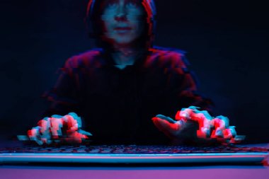 Kapüşonlu hacker karanlık odada bilgisayar yazma metni ile çalışıyor. Glitch efektli görüntü