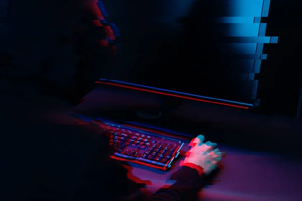 Hacker en el capó trabajando con la computadora escribiendo texto en la habitación oscura. Imagen con efecto glitch —  Fotos de Stock