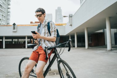 Bisikletinin yanında poz veren adam.