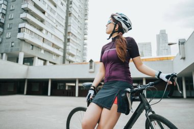 Bisikletinin yanında poz veren kadın.