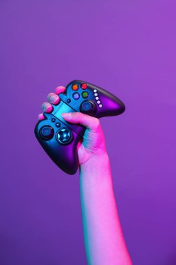 Mor arka planda siyah gamepad ile el.