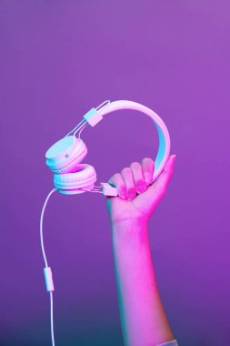 Mor arka planda beyaz kulaklıklı eller.