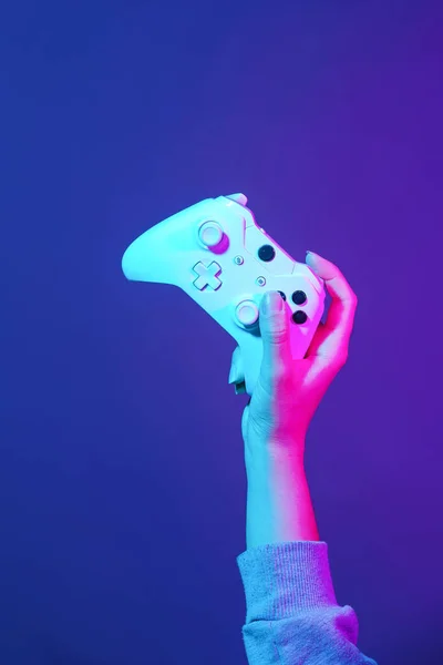 Hand mit weißem Gamepad auf dunkelviolettem Hintergrund. — Stockfoto