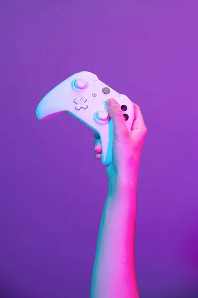 Mor arka planda beyaz gamepad ile el. — Stok fotoğraf