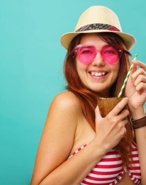 Mayo ve hasır şapka giyen kadın renkli turkuaz arka plan üzerinde kakao sütü içiyor