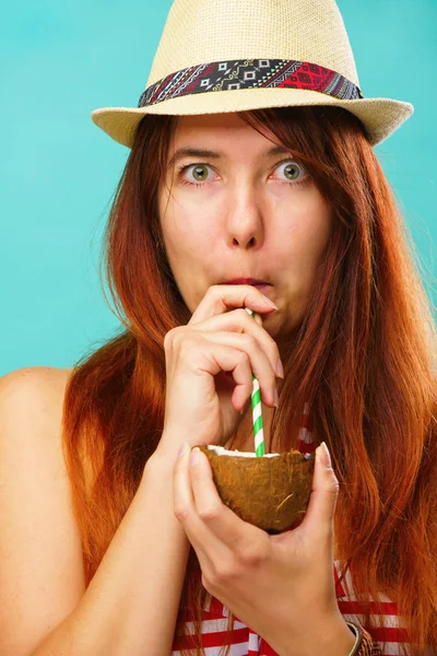 Η γυναίκα που φοράει μαγιό και ψάθινο καπέλο πίνει γάλα καρύδα πάνω από Πολύχρωμο τυρκουάζ φόντο — Φωτογραφία Αρχείου