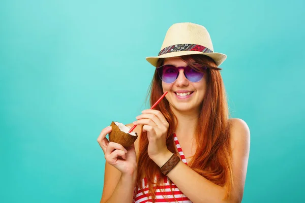 Mujer con un traje de baño y sombrero de paja bebe leche de coco sobre fondo de color turquesa — Foto de Stock