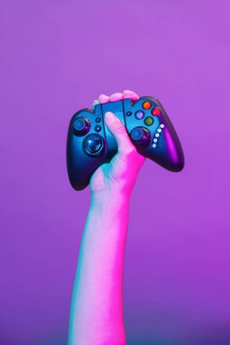 Mor arka planda siyah gamepad ile el.