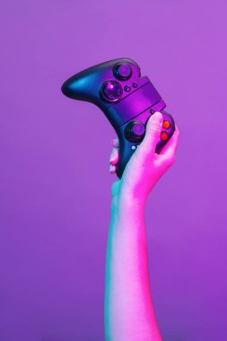 Mor arka planda siyah gamepad ile el.