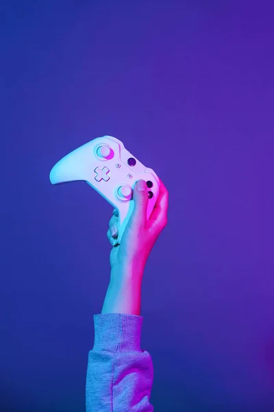 Ręka z białym Gamepad na ciemnym fioletowym tle. — Zdjęcie stockowe