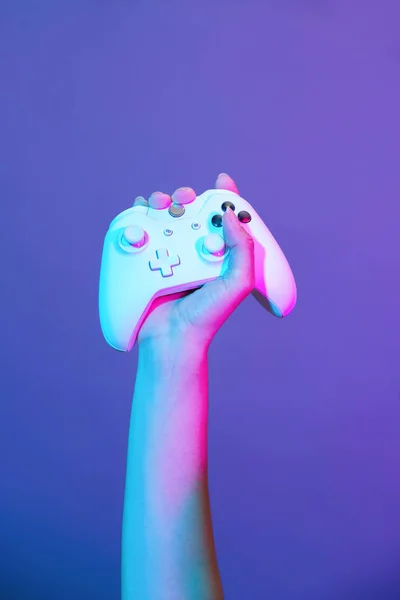 Mão com gamepad branco no fundo violeta . — Fotografia de Stock