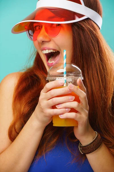 Mujer con un traje de baño azul, sombrero y gafas de sol bebe jugo de frutas de una taza — Foto de Stock