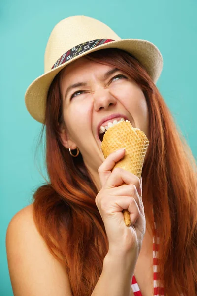 水着と麦わら帽子をかぶった女性は、カラフルなターコイズの背景の上にカップからアイスクリームを食べる — ストック写真