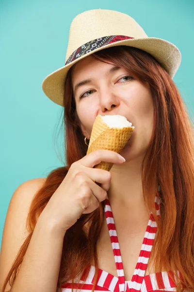 Mujer con un traje de baño y sombrero de paja come helado de la taza sobre fondo de color turquesa — Foto de Stock