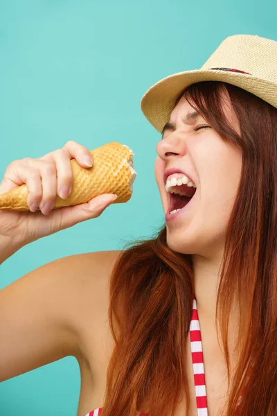 Mujer con un traje de baño y sombrero de paja come helado de la taza sobre fondo de color turquesa — Foto de Stock