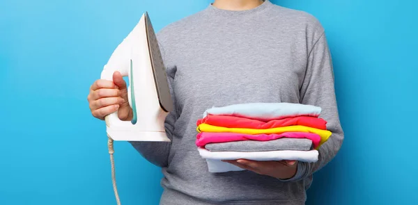 Women with electric iron and pile of clothes in her hands. — Stock Photo, Image