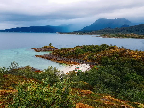 Foto de pintoresca zona montañosa, coloridos kayaks en la orilla del mar de arena en Noruega . — Foto de Stock