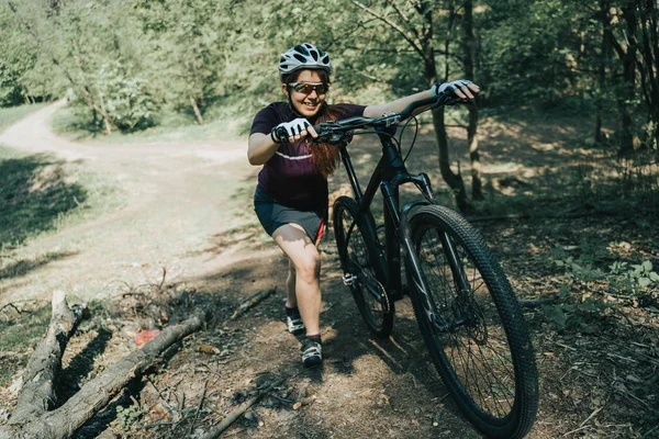 Zdjęcie Sportsmen w kask podnoszenia rowerów na wzgórzu w lesie — Zdjęcie stockowe