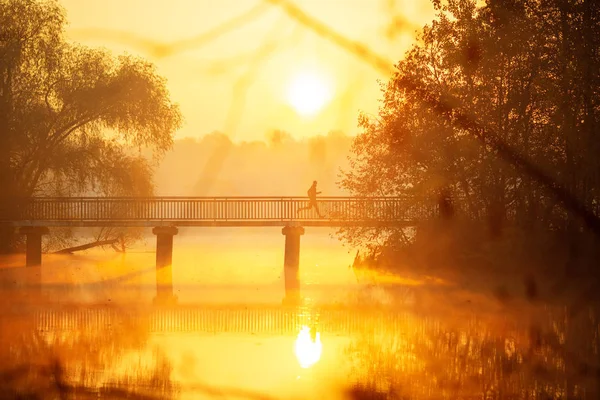 O homem atravessa a ponte ao nascer do sol. . — Fotografia de Stock