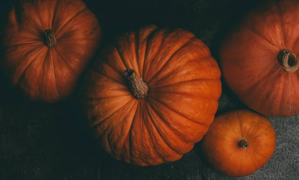 Foto de arriba de cuatro calabazas naranjas sobre fondo negro, celebración de Halloween —  Fotos de Stock