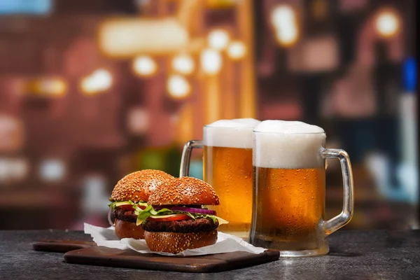 Dos tazas heladas de cerveza ligera y dos hamburguesas — Foto de Stock