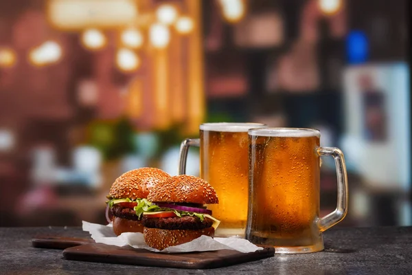 Dos tazas heladas de cerveza ligera y dos hamburguesas — Foto de Stock