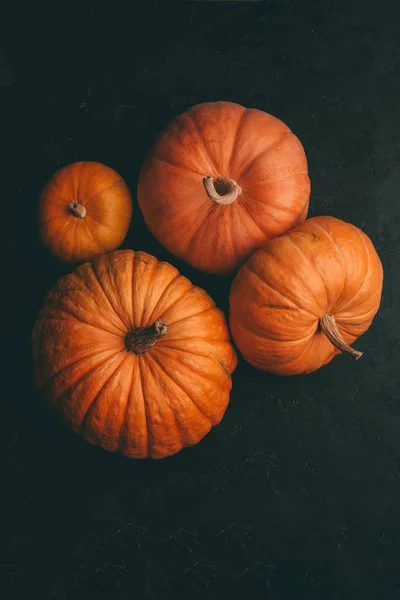 Fotografie ze čtyř oranžových dýně na černém pozadí, oslava Halloweenu — Stock fotografie