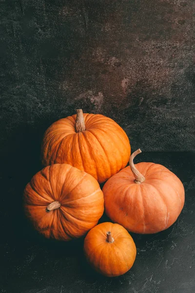 Foto de cuatro calabazas naranjas sobre fondo negro, celebración de Halloween . —  Fotos de Stock