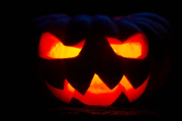 Photo rapprochée d'une citrouille d'Halloween avec des bouches brûlantes sur fond noir vide — Photo