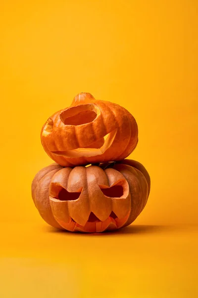 Afbeelding van twee Halloween pompoenen op lege oranje achtergrond. — Stockfoto