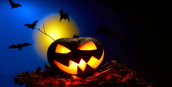 Foto de uma abóbora com boca ardente, morcegos à noite — Fotografia de Stock