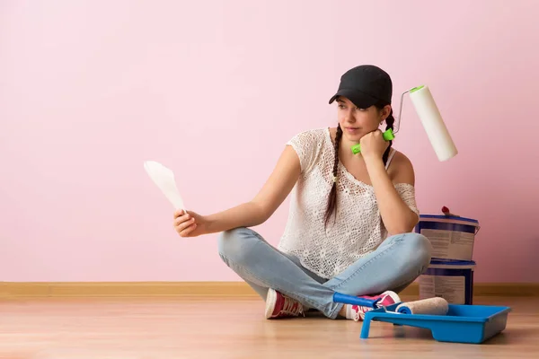 Mujer con rodillo de pintura y paleta de colores sentada en el suelo — Foto de Stock