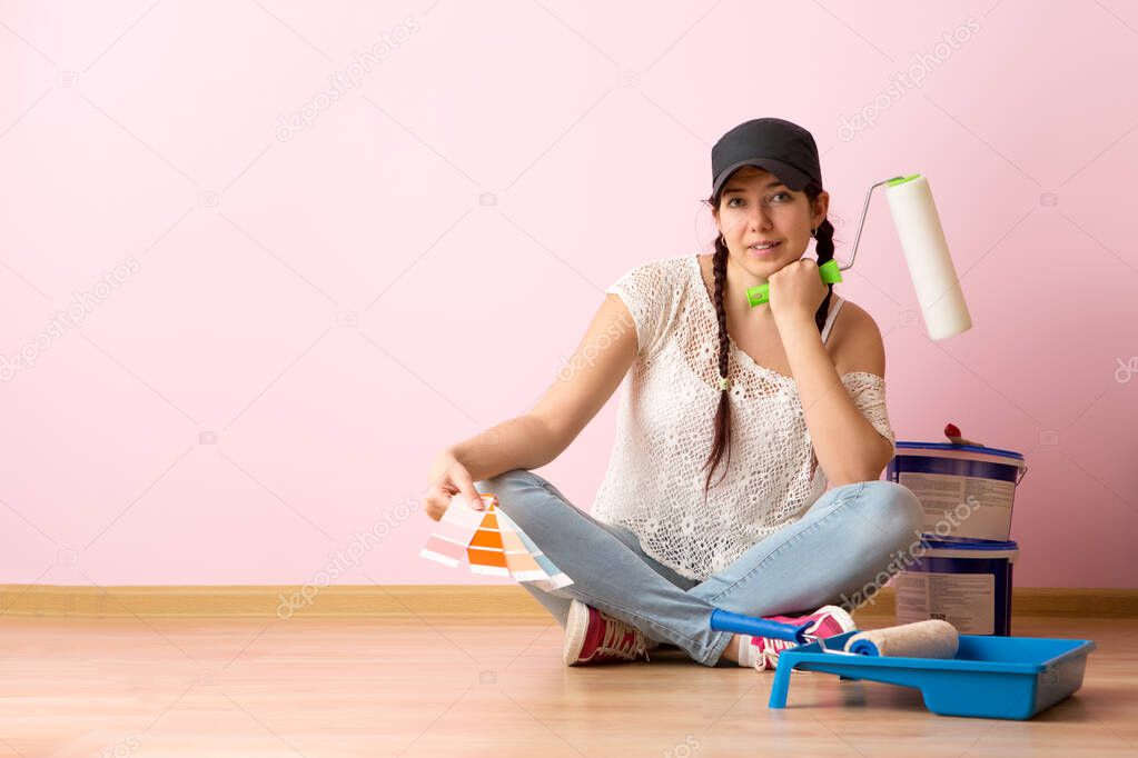 Woman with paint roller and color palette sitting on the floor