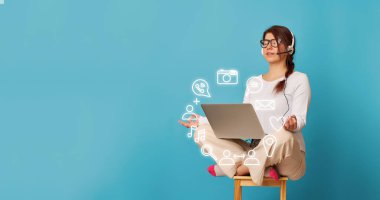 Kadın Lotus pozisyonunda dizüstü bilgisayarı olan bir sandalyede oturuyor..