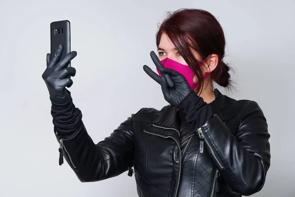 Žena v ochranné masce, aby se zabránilo šíření Coronavirus komunikuje přes smartphone. — Stock fotografie
