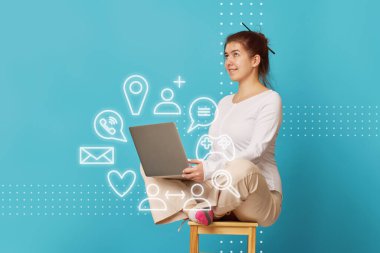 Kadın Lotus pozisyonunda dizüstü bilgisayarı olan bir sandalyede oturuyor..