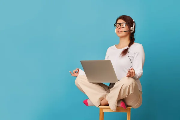 Mulher está sentada na posição de lótus em uma cadeira com um laptop . — Fotografia de Stock