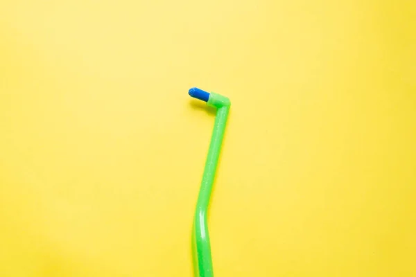 Green toothbrush with a single beam for braces on a yellow background — Stock Photo, Image