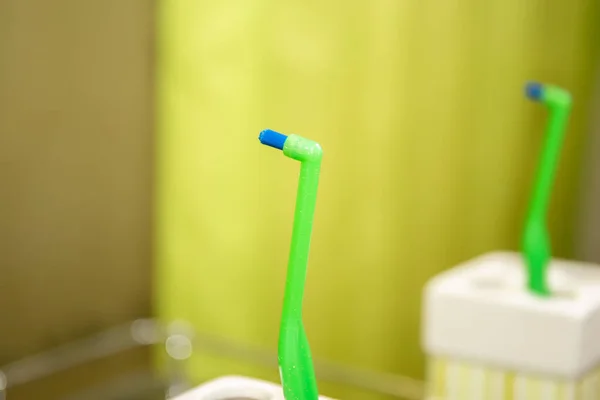 Zielona szczoteczka do zębów z pojedynczym kępkiem na aparat w łazience — Zdjęcie stockowe