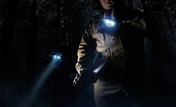 茶色の戦術的なジャケット 手袋ナイフを使用して 夜の森背景に頭懐中電灯で道を照明で男性 人の写真 — ストック写真