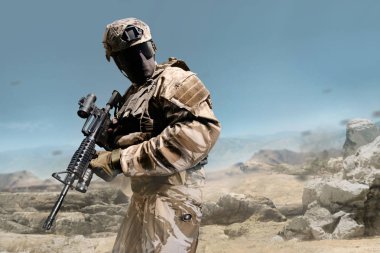 Profil görünümü askeri asker tüfeği çöl arka plan üzerinde poz kıyafeti tam donanımlı.