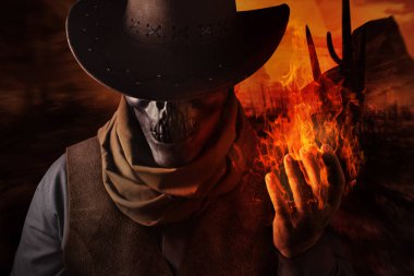 Şeytani kafatası baş kovboy şapkalı bir gün batımı çöl arka plan üzerinde ateş büyü kolunu tutarak fotoğrafı.