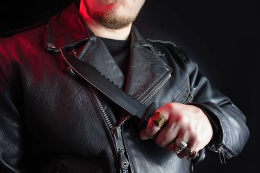 Biker in leather jacket holding hunting knife. clipart
