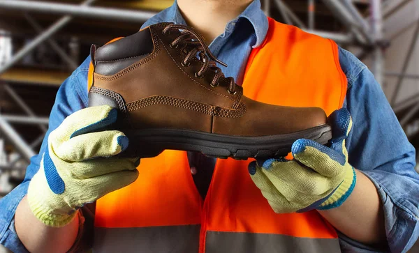 Trabalhador em roupa de jaqueta laranja segurando boot . — Fotografia de Stock